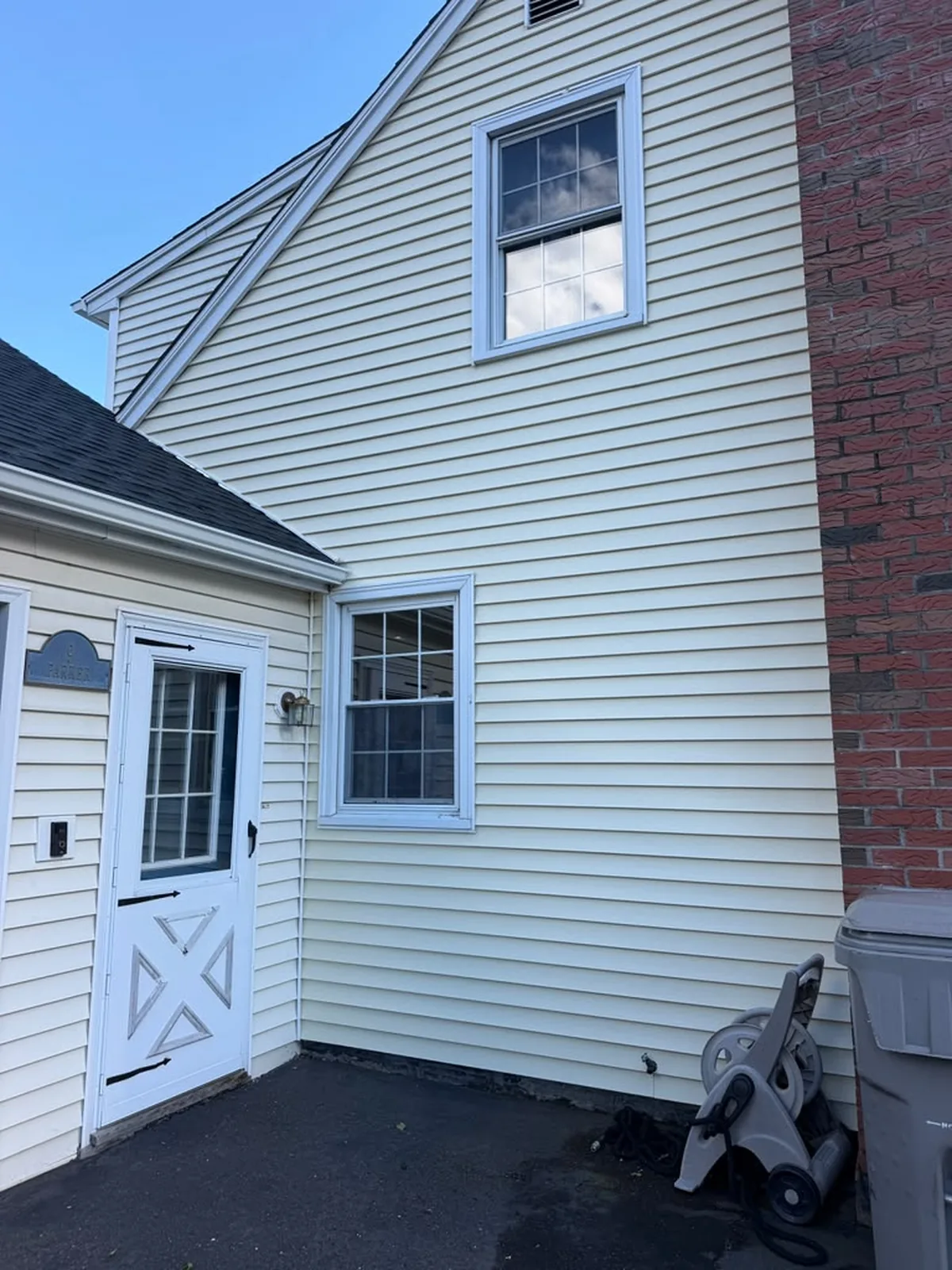 Cream vinyl siding detail with storm door and soffit